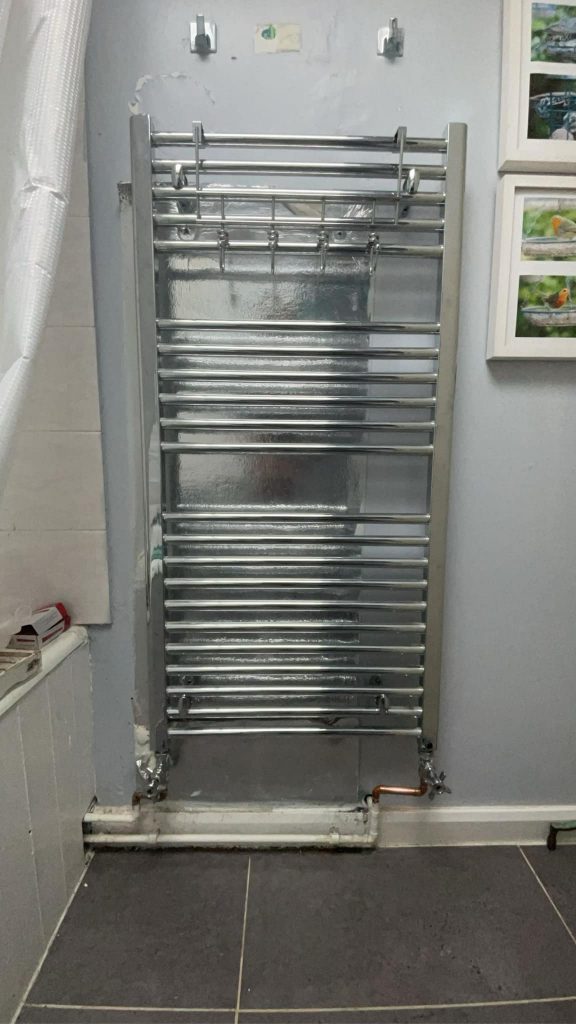AFTER: New, sleek bathroom radiator with a shiny finish and modern design.