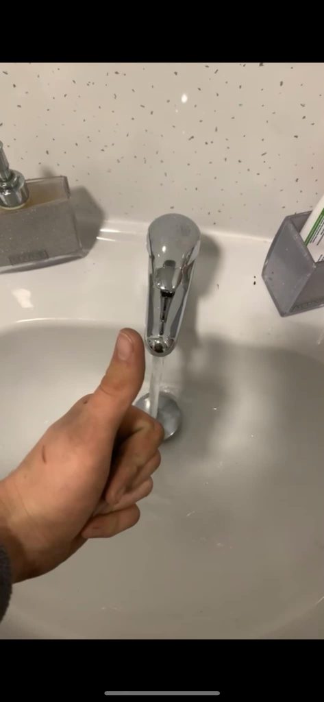 Success: The image shows a newly installed tap in a customer's home, with a thumbs-up gesture signalling a job well done after replacing a faulty tap.