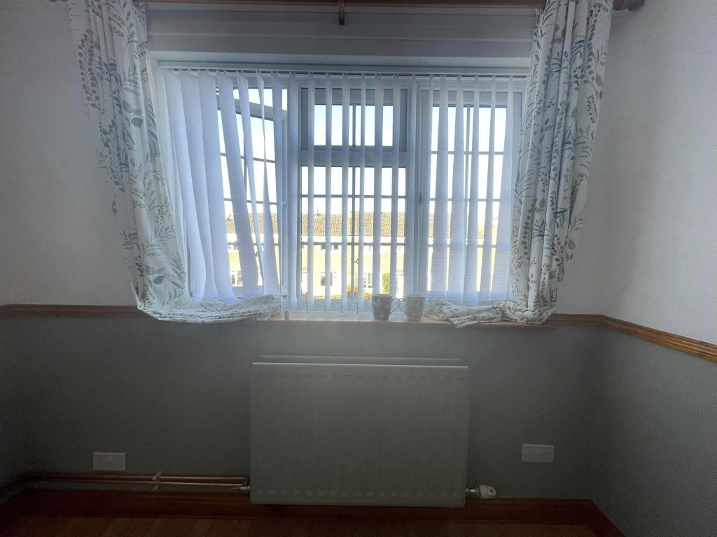 Newly installed radiator under a window in a tidy room, indicating job completion.